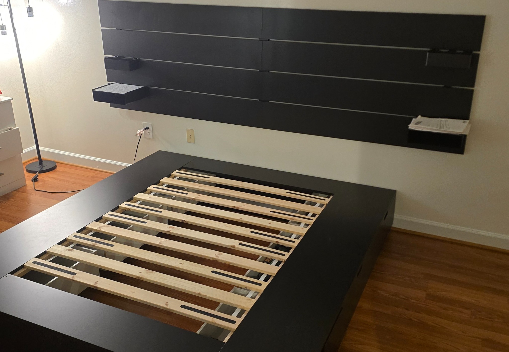 Large black bed frame and wall-mounted headboard assembled in bedroom