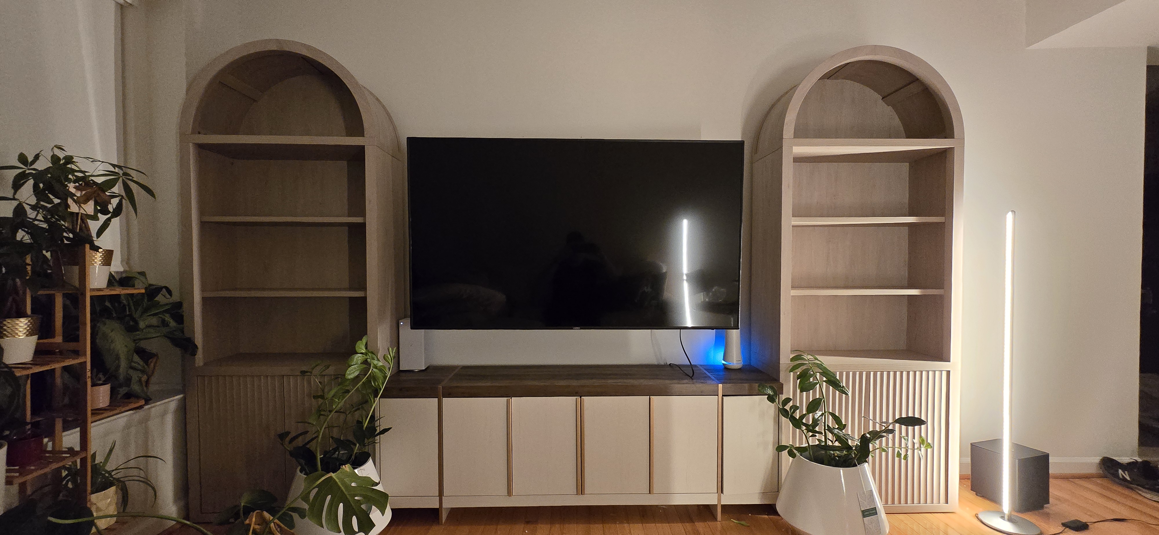 Wall-mounted TV above an assembled TV stand, flanked by two assembled arched bookcases